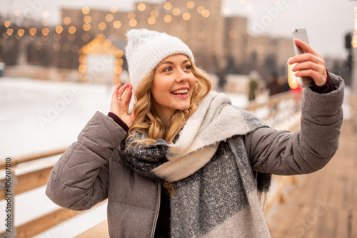 The girl is filming her video blog at the New Year's fair. In the background we see a skating rink
