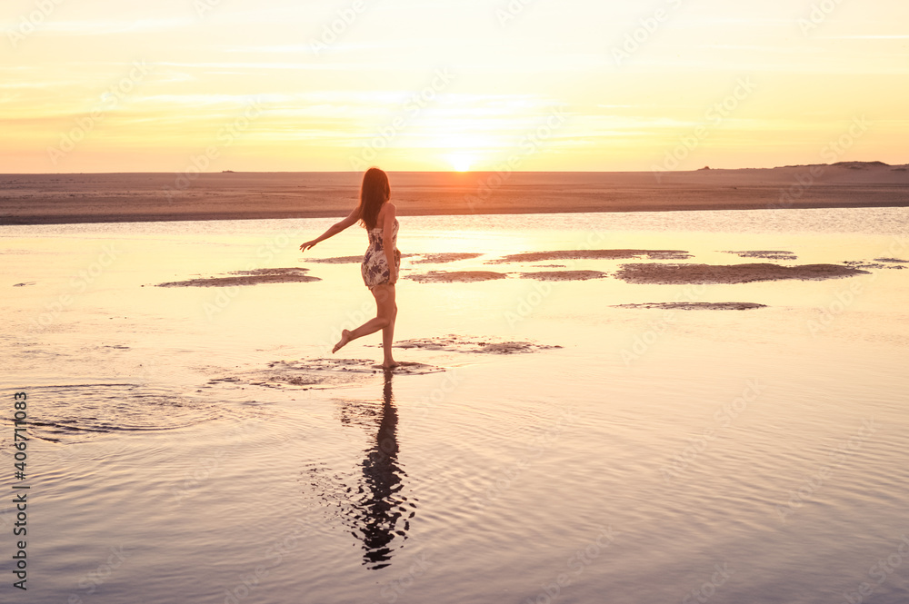 Beautiful lady running on golden water into the sunset with reflection