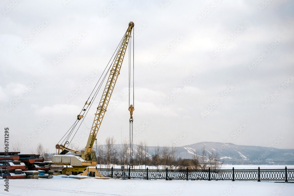 Fototapeta premium Construction crane on a winter day on a frozen river