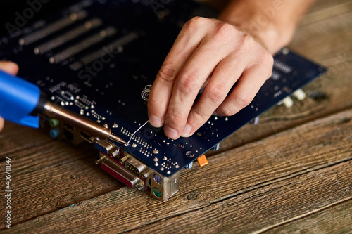 Engineer or technician repair electronic circuit board with soldering iron.