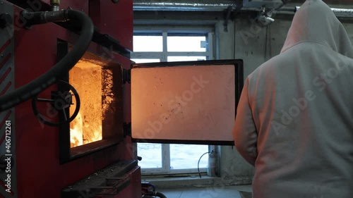 Boiler room on environmentally friendly fuel .stoker boiler room worker who throws wooden bars into the boiler. firewood burns in furnace, burning process, house heating, winter season photo