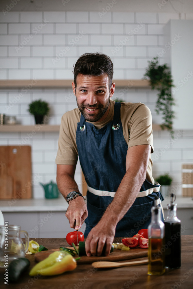 Close up of man cutting vegetables. Attractive man cooking in modern kitchen.. Close up of man cutting vegetables. Attractive man cooking in modern kitchen..