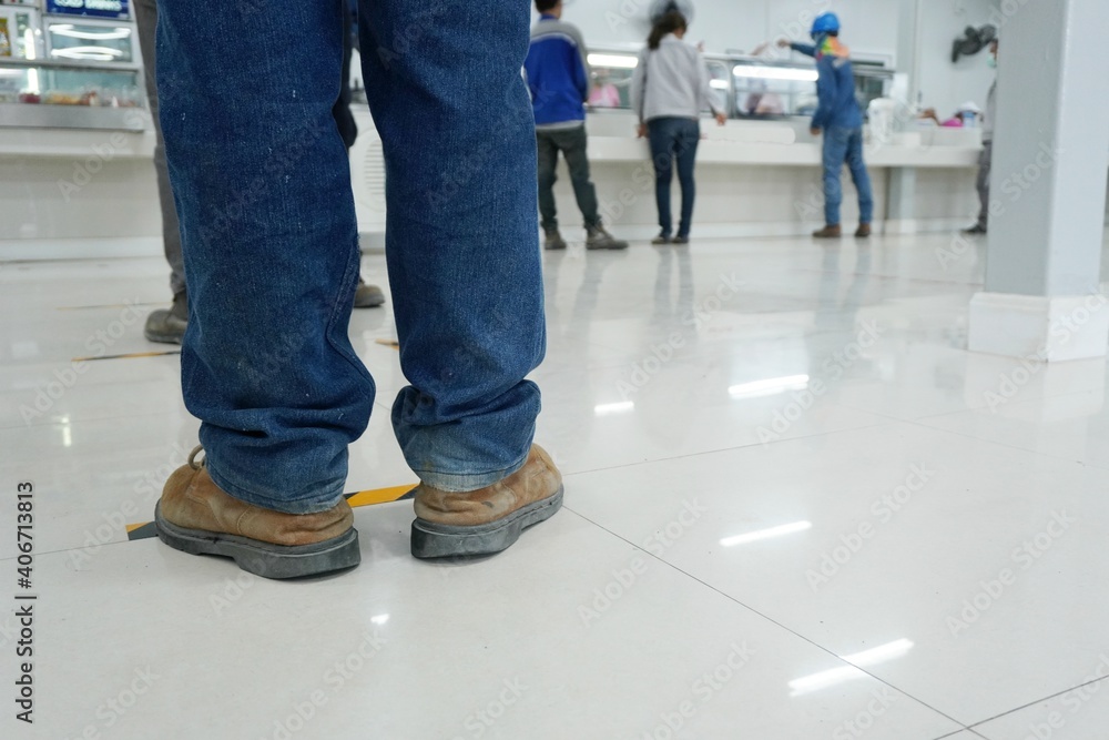 Worker stands before the yellow-black line up to wait to buy food in the factory canteen room during corona virus epidemic. (Covid 19) Worker stands before the yellow-black line up to wait to buy food in the factory canteen room during corona virus epidemic. (Covid 19)