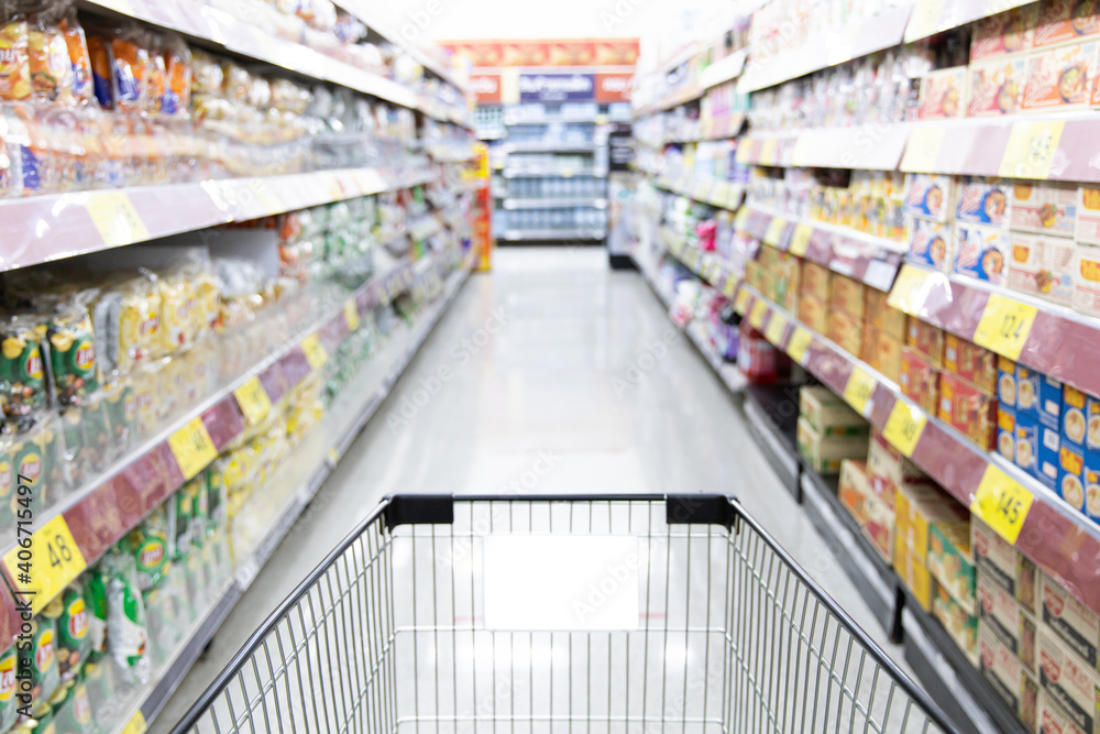 Shopping cart in supermarket, Abstract blurred photo in shopping malls, Cart in the market, wide variety of products are placed on the shelves for an orderly display.