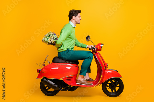 Full length profile photo of nice guy driving bike hold flower behind back wear sweater isolated on yellow color background © deagreez