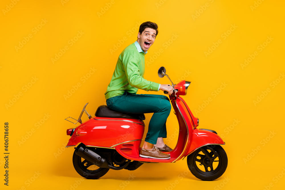 Full length profile photo of handsome guy driving moped open mouth wear sweater isolated on yellow color background
