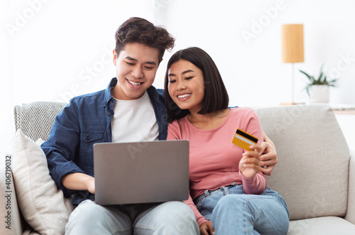 Japanese Couple Shopping Online Using Laptop And Credit Card Indoor