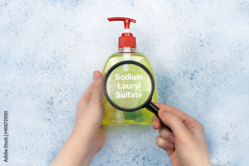 A bottle of Liquid soap floating in soapy water. Harmful ingredients, detergent with Sodium Lauryl Sulfate. The concept of hazardous substances in cosmetics and household chemicals photo