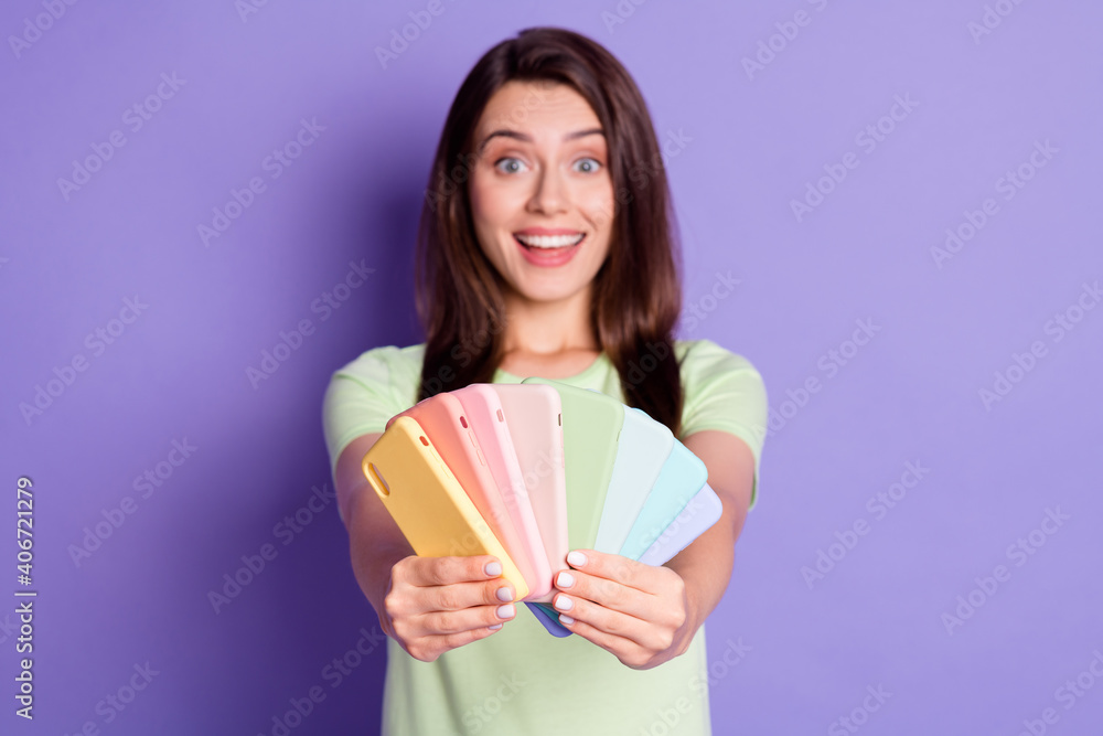 Photo portrait of girl holding many phones with two hands close to camera isolated on vivid purple colored background Photo portrait of girl holding many phones with two hands close to camera isolated on vivid purple colored background