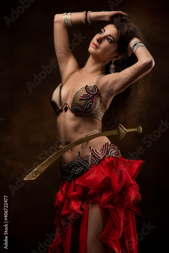 Oriental dancer with a saber. Belly dance. The brunette. Red.