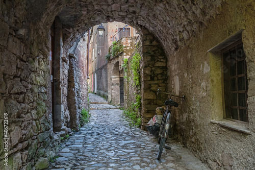 Fototapeta Naklejka Na Ścianę i Meble -  View of empty stone streets of an abandoned mountain village with a few remaining residents. Forgotten old bike parked against the wall