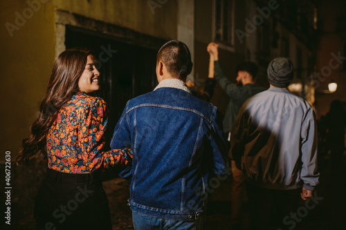 happy group of friends at night out together in the streets of city