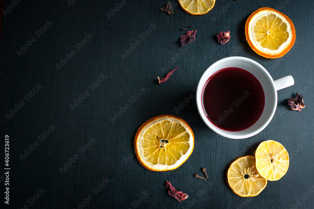 Hibiscus tea with dried orange and lemon slices on black table. Top view still life