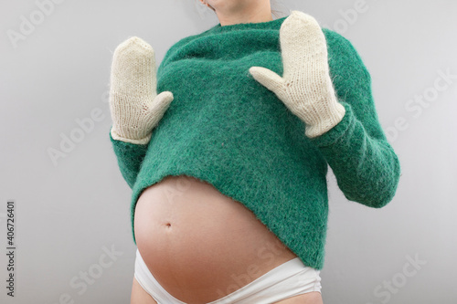 Pregnant woman in a woolen sweater and warm mittens