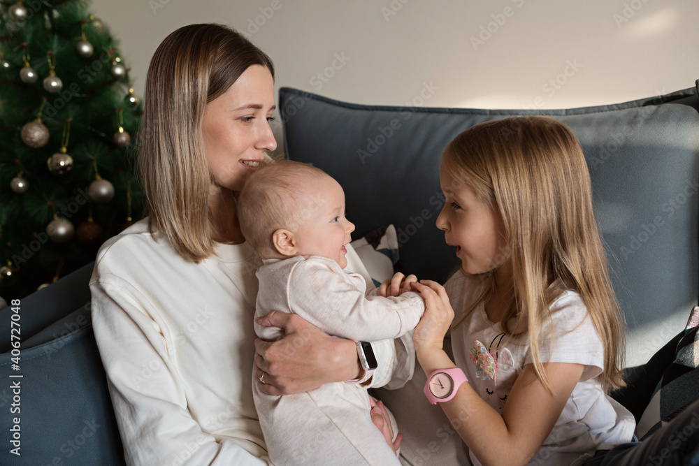 Young caucasian mother having fun on couch with two children at home during coronavirus covid-19 quarantine. Social Distancing and Self Isolation. Mother's day celebration, weekend concept.