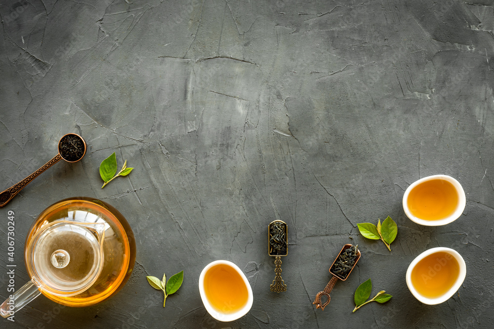 Tea green leaves with teapot and cups, top view. Tea ceremony concept.