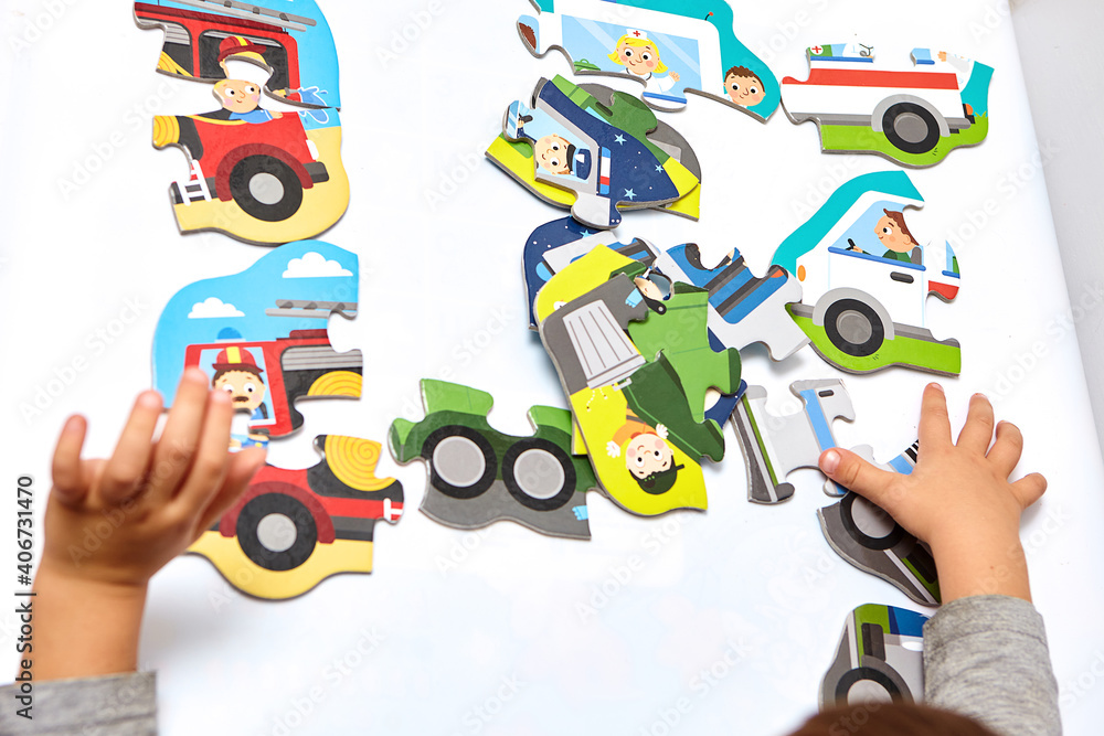 Fototapeta premium Child playing with puzzles,. The boy is playing in his room. Educational logic toys for kid's..