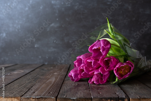 Atmospheric mothers day decoration with bouquet of pink tulips and gift on dark vintage wood. Space for text. photo