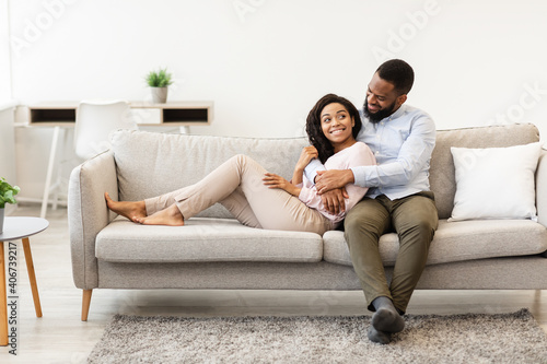 African american couple spending weekend together lying on couch