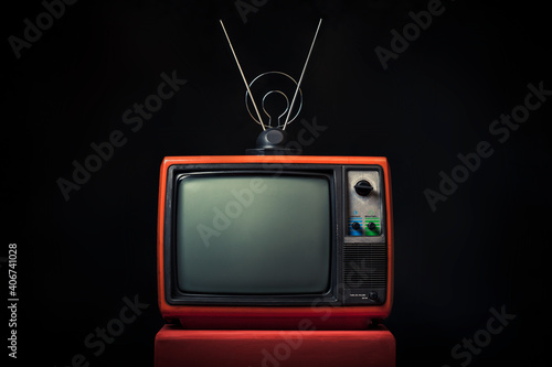 Retro old red TV with antenna on wooden box on black background. photo