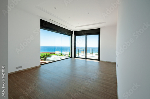 Empty room with large panoramic windows overlooking the sea. Room after major renovation.