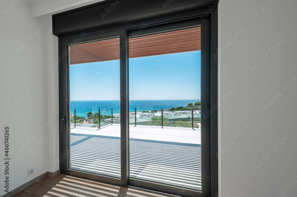 Empty room with large panoramic windows overlooking the sea. Room after major renovation.