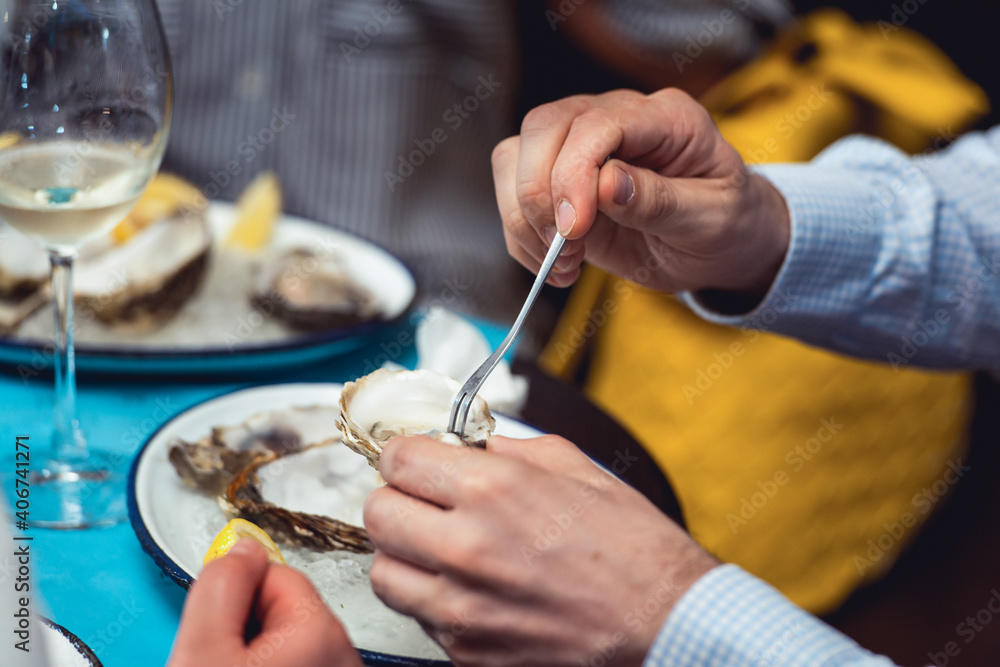 man eating oyster shellfish in a seafood restaurant. yellow toning, selective focus man eating oyster shellfish in a seafood restaurant. yellow toning, selective focus
