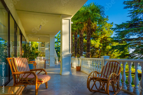The veranda of the house with armchairs on the background of palm trees.