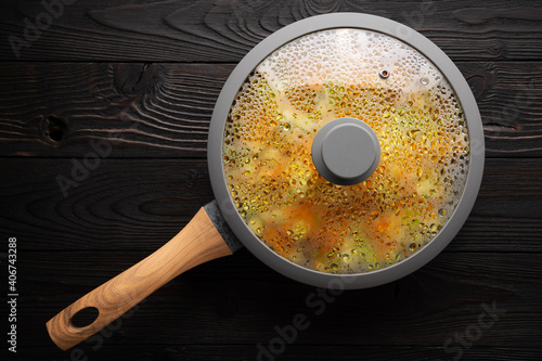 fresh stewed vegetables in a frying pan on a wooden background, flat lay photo