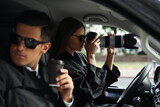 Private detectives with modern camera spying from car