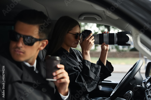 Private detectives with modern camera spying from car photo