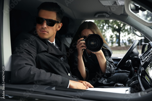 Fotografie Private detectives with modern camera spying from car