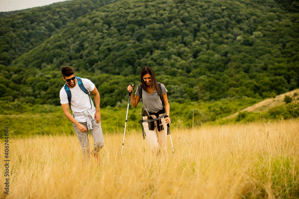 Smiling couple walking with backpacks over green hills