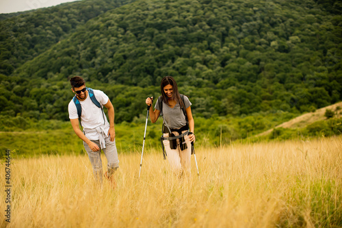 Smiling couple walking with backpacks over green hills