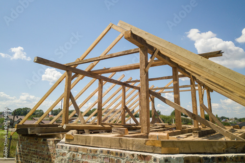 Aerial view of unfinished house with wooden roof frame structure under construction.