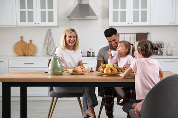 Happy family having breakfast together at table in modern kitchen