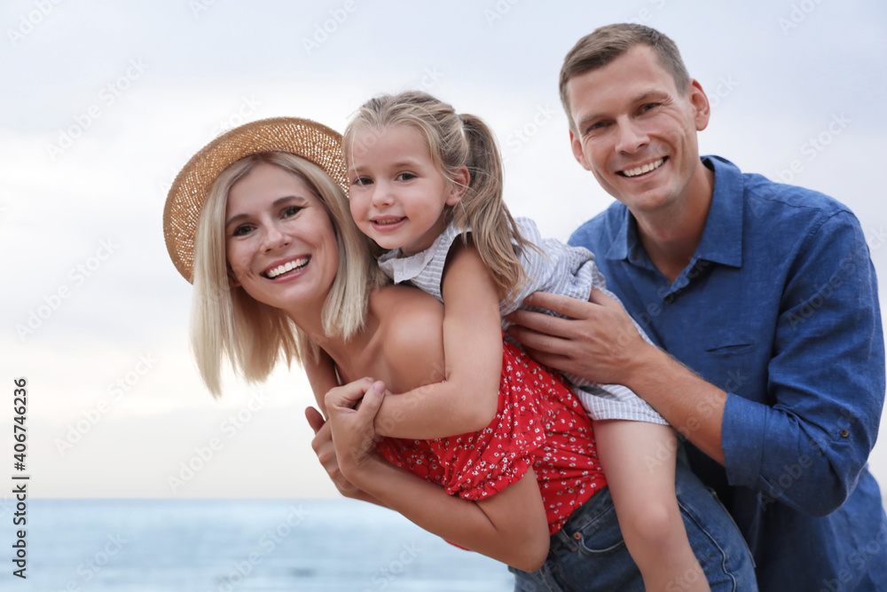 Happy family spending time together near sea on sunny summer day