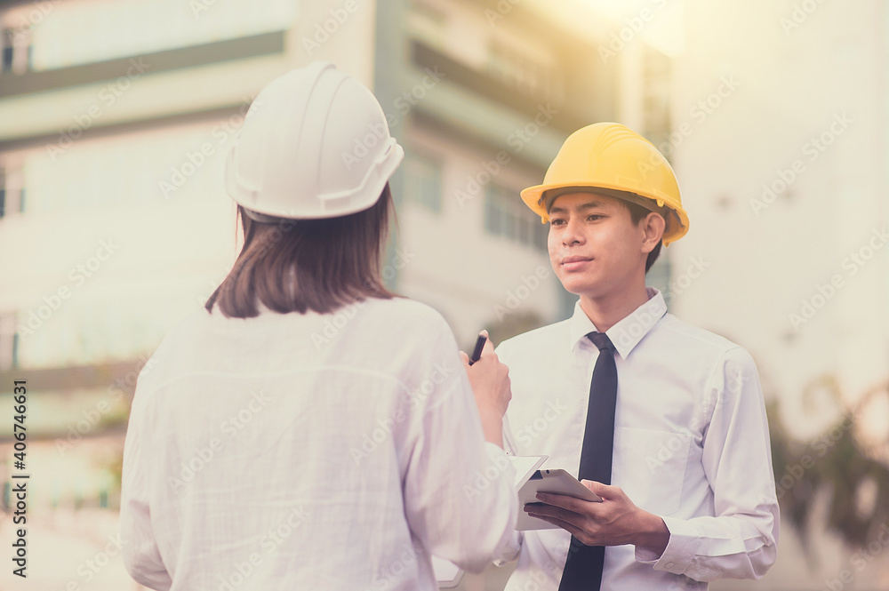 Two Asian businesspeople talking and meeting record on clipboard about building civil project Two Asian businesspeople talking and meeting record on clipboard about building civil project