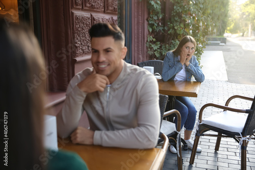 Fotografie Jealous ex girlfriend spying on couple in outdoor cafe
