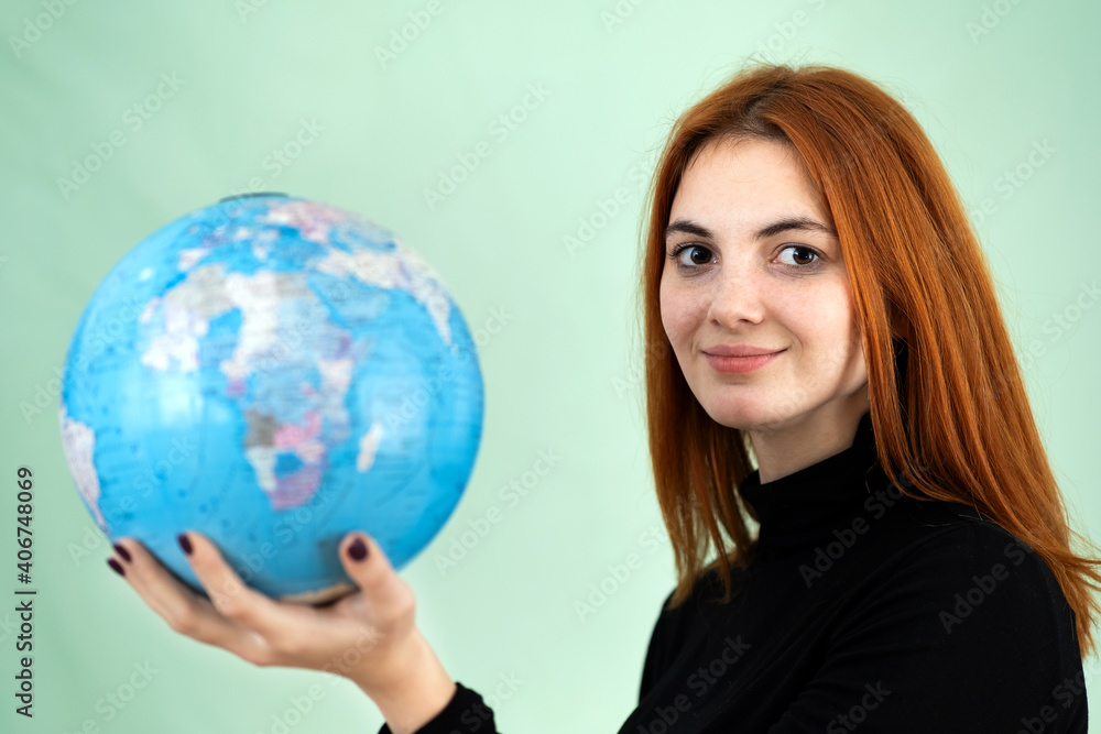 Portrait of a happy young woman holding geographic globe of the world in her hands. Travel destination and planet protection concept. Portrait of a happy young woman holding geographic globe of the world in her hands. Travel destination and planet protection concept.