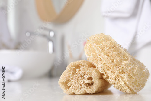 Natural loofah sponges on table in bathroom, closeup. Space for text photo