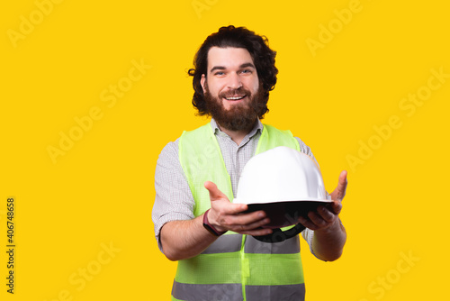 Photo of cheerful architect man giving you a hard hat for protection.