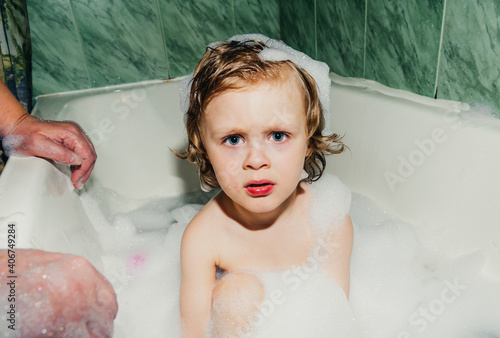 beautiful child toddler son washes in the bathroom plays has fun with soap bubbles,foam