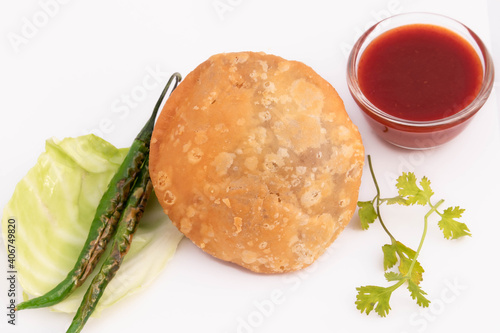 Deep Fried Indian Delight Street Food Moong Dal Kachauri Or Urad Masala Daal Khasta Kachori Kachodi Served With Tomato Sauce And Green Chilli. Isolated On White Background With Blank Space For Text photo