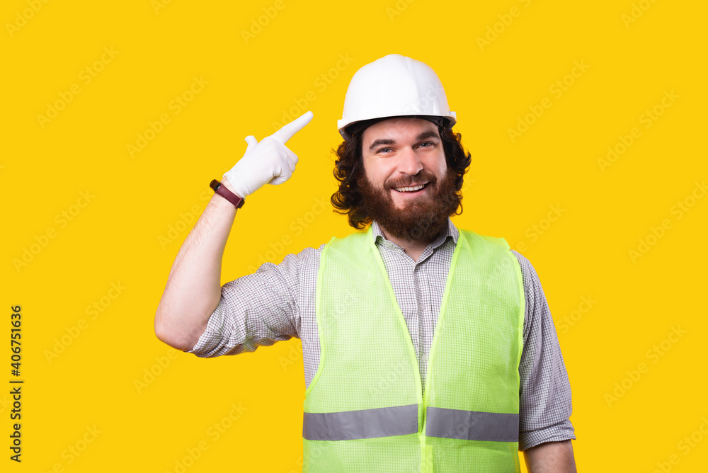 Photo of handsome bearded architect man pointing at hard hat. Photo of handsome bearded architect man pointing at hard hat.