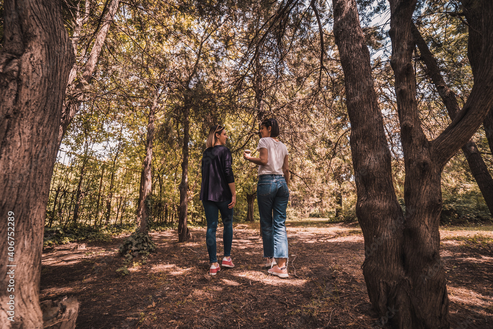 Fototapeta premium Two happy young women having coffee break together in park