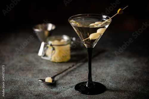 Gibson alcohol cocktail with martini and onions in martini glass. Decorated cocktail on dark background photo