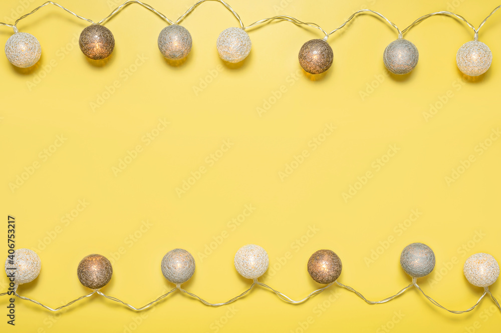 Fototapeta premium Gray white festive garland on yellow background flat lay top view. Cotton Balls Garland. Round bulbs LED festoon lights electric garland. Festive decoration Colors year 2021 Illuminating Ultimate gray