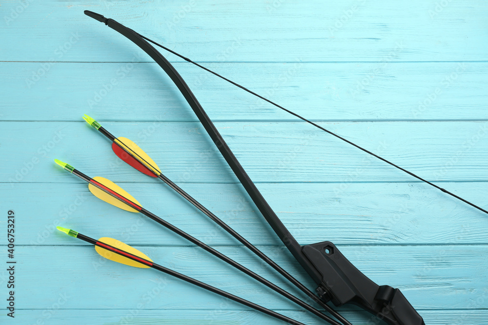 Plastic arrows and bow on turquoise wooden table, flat lay. Archery sports equipment Plastic arrows and bow on turquoise wooden table, flat lay. Archery sports equipment