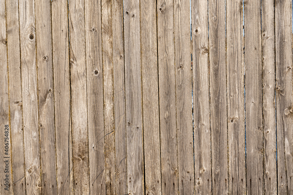 Naklejka premium close-up of an old wooden fence where you can see the structure and direction of the boards, which have dry large bends in the foreground